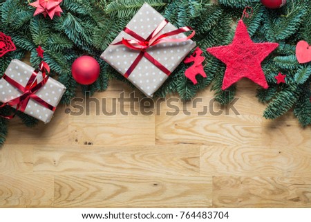 Christmas background border at the top with fir branches and other decorations like presents red stars and bulbs with copy space on a wooden table