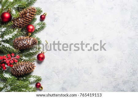 Christmas background. Snow Fir tree branch, pine cones, red balls and berries on gray stone table. Top view with copy space.