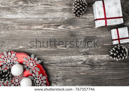 Upper, top view, of Christmas presents and a plate with homemade decorative snowflakes on a wooden brown rustic background, with space for text writing.