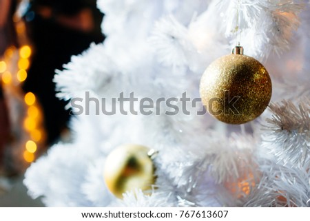 Golden mirrored disco balls and Christmas decorations against white bokeh and yellow abstract background. Christmas tree decorated with mirror disco globe on holiday.