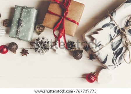 wrapped present boxes with ornaments pine cones anise on white wooden background top view, space for text. christmas flat lay. seasonal greetings card. happy holidays.
