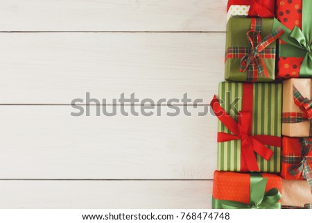Christmas gift boxes in colorful wrapping paper decorated with checkered ribbon on white wooden background, copy space, top view
