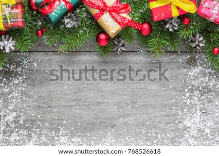 Christmas background with fir branches, red balls, gift boxes and pine cones on rustic wooden table covered with snow. Flat lay. top view with copy space
