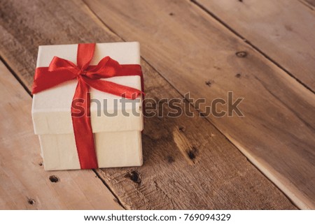 small white gift box with red ribbon on wood table