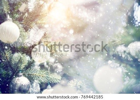 Christmas holiday background. Silver and white bauble hanging from a decorated on christmas tree with bokeh and snow, copy space.