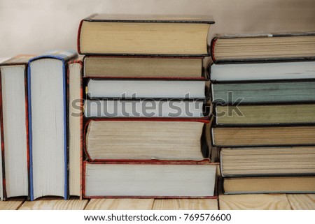 Textbooks and books on a wooden table. Book stack in the library room and blurred bookshelf for business and education background. 