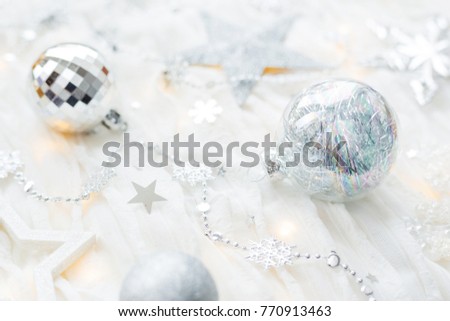Christmas and New Year holiday background with decorations and light bulbs. Silver and white shining balls, snowflakes and star confetti.