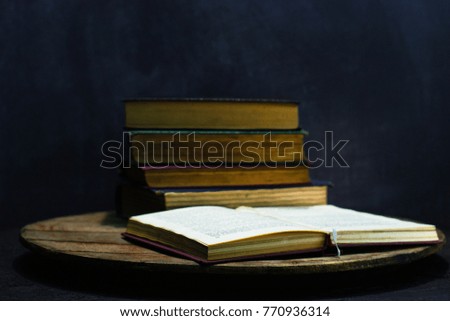 Old books on a round wooden table. Beautiful dark background.