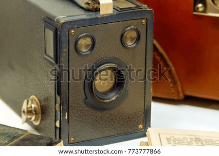Macro close-up of an old photographic camera next to a briefcase and papers