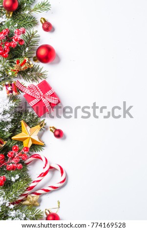Christmas background. Red and gold christmas decorations with snow fir tree branch on white background. Top view with copy space. Vertical.