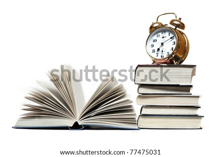 Alarm clock standing on stack of books near open book