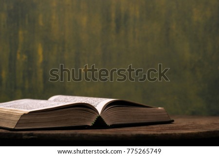 Bible on a old round wooden table.  Beautiful gold background.Religion concept.