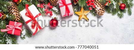 Christmas background. Red christmas present box, fir tree branch and decorations on gray stone table. Long banner format.
