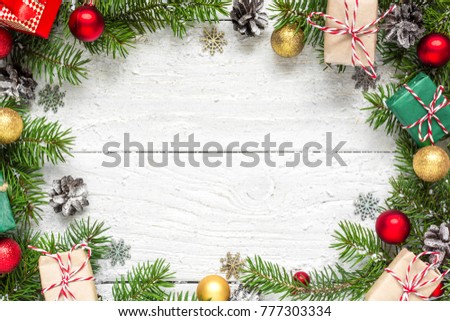 Christmas frame made of fir branches, red and golden decorations, gift boxes and pine cones on white wooden table. Christmas background. Flat lay. top view with copy space