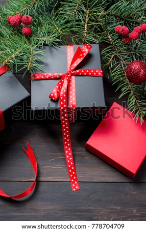 red Christmas background. black gift box,  balls, fir branches,red Christmas decorations on the dark wooden background  copy space