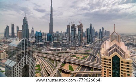 Dubai downtown skyline timelapse at sunset with beautiful city center skyscrapers and Sheikh Zayed road traffic. Top aerial view from tower rooftop. Clouds on the sky. Dubai, United Arab Emirates