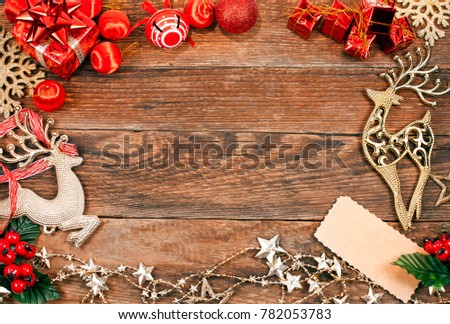 Christmas greeting card. Golden and red balls, deer, red berries, gift boxes and label on a wooden background. Top view. Text space.