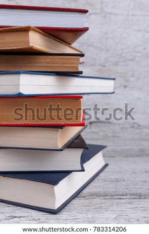 A large stack of different bookson a wooden background. The concept of education. Close-up.