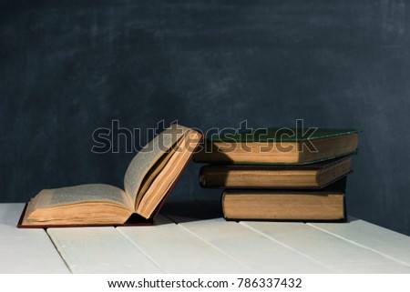 Textbooks and books on a white wooden table. Beautiful dark background.