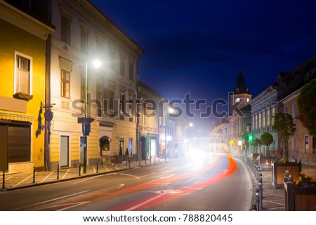 View of illuminated Brasov streets with clock tower of city Council at night