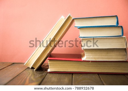 stack of books on wooden table and pink background. Back to school. Copy space for text.