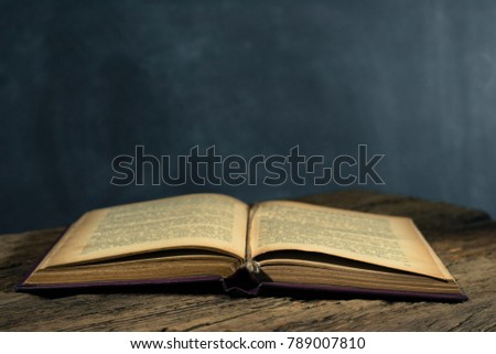 One open old book on a old oak wooden table. Beautiful dark background.