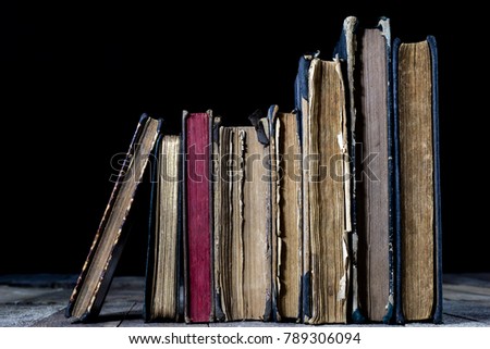 Old destroyed books on a wooden table. Reading room library with very old books on a wooden table. Black background.