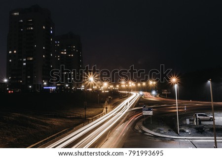 High-rise buildings and roads at night with traces of car headlights in the fog