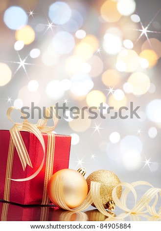 christmas present and baubles against bokeh lights background