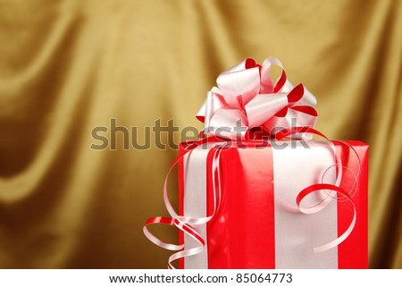 Christmas gift in a red box with a silver bow on golden background