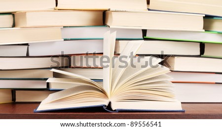 Stack of books and opened book on the table