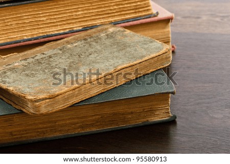 Heavily worn antique books piled on a wood table